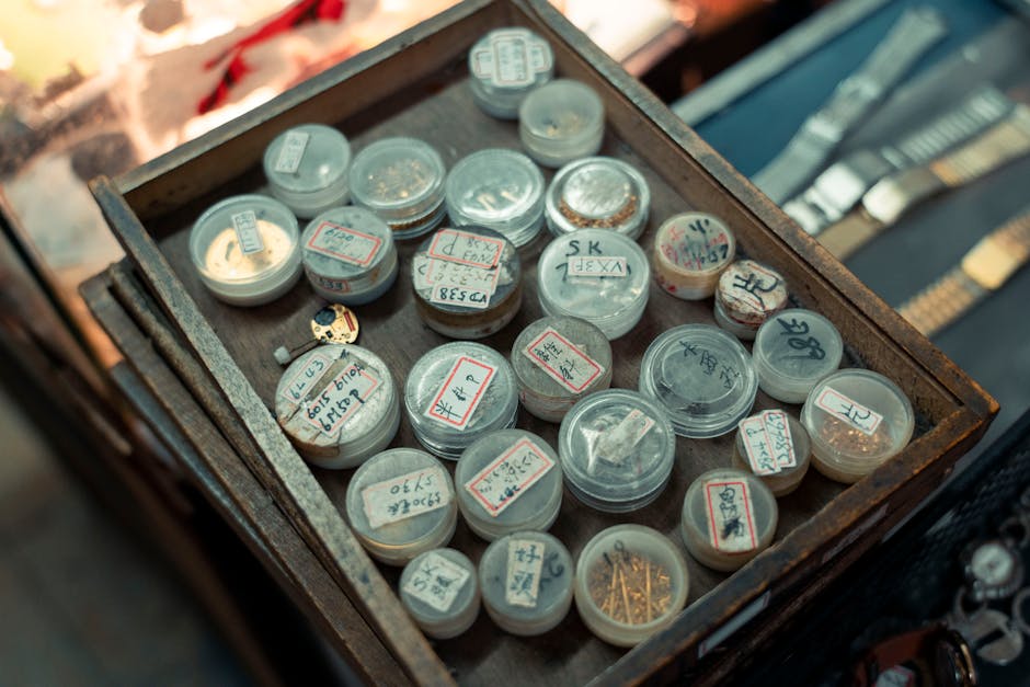 A detailed close-up of antique watchmaking tools and parts in a wooden box, creating a vintage workshop feel.