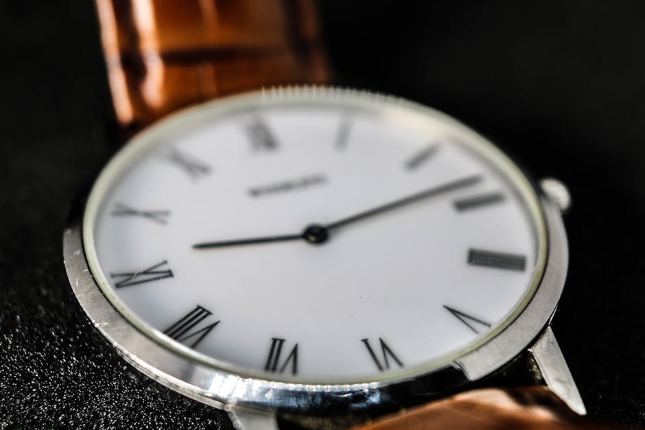 Close-up shot of an analog wristwatch with roman numerals and leather strap.